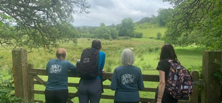 Four people looking over a fence in a field 